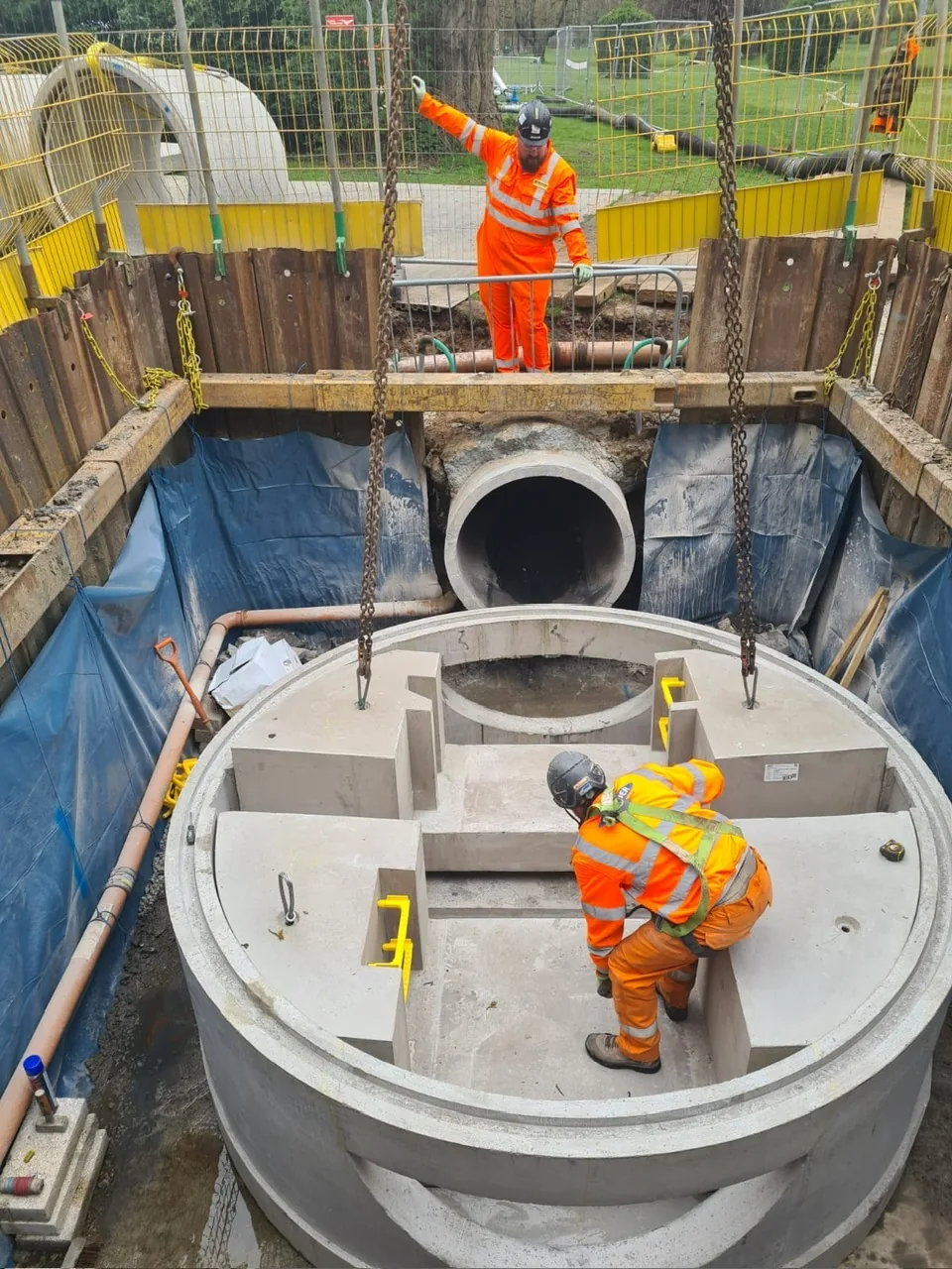 Workers lowering precast concrete manhole into sheeted excavation on Kilburn to Marehay rising main project, Derbyshire